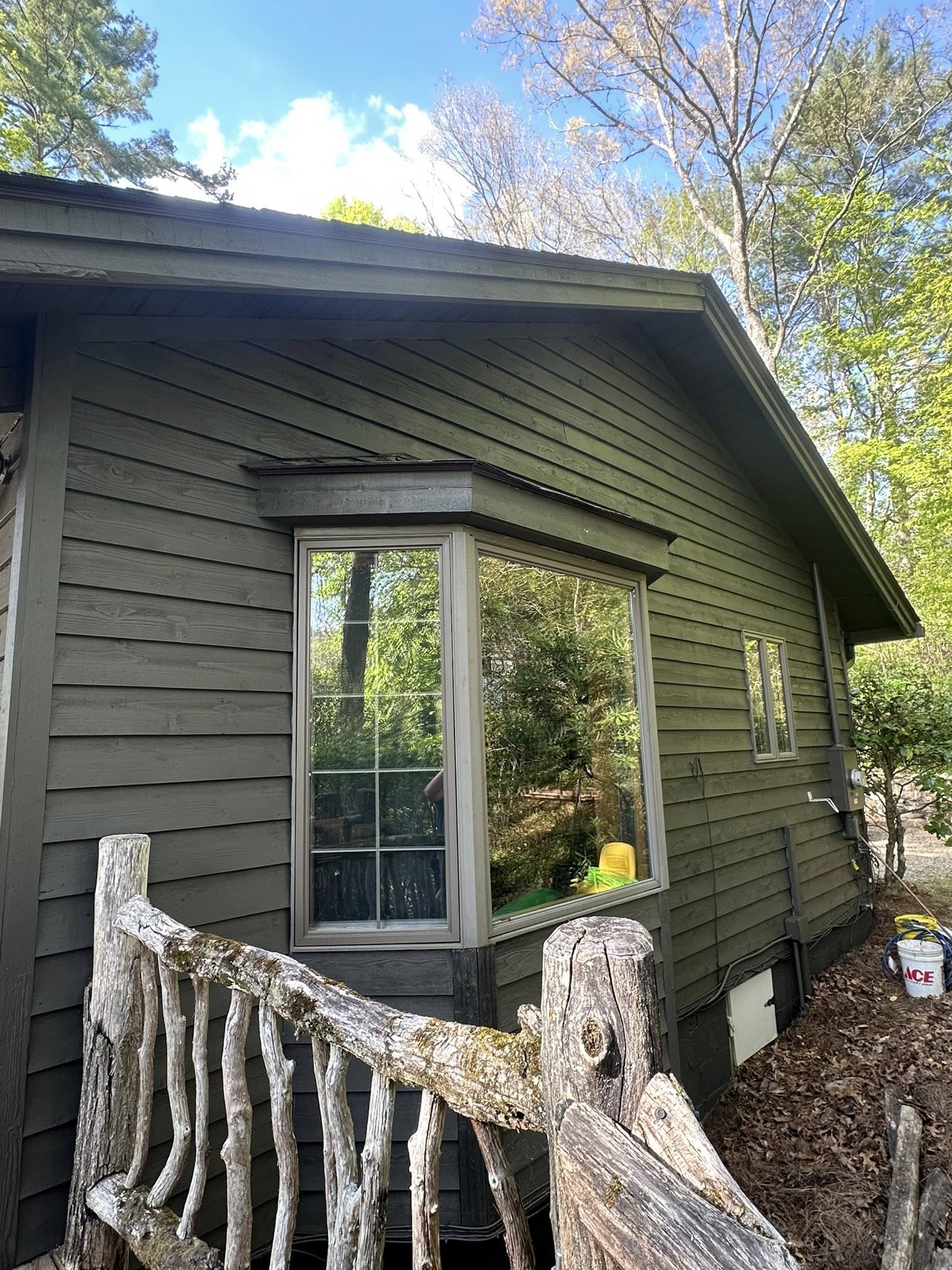 Dark olive lap siding on a wooded home exterior
